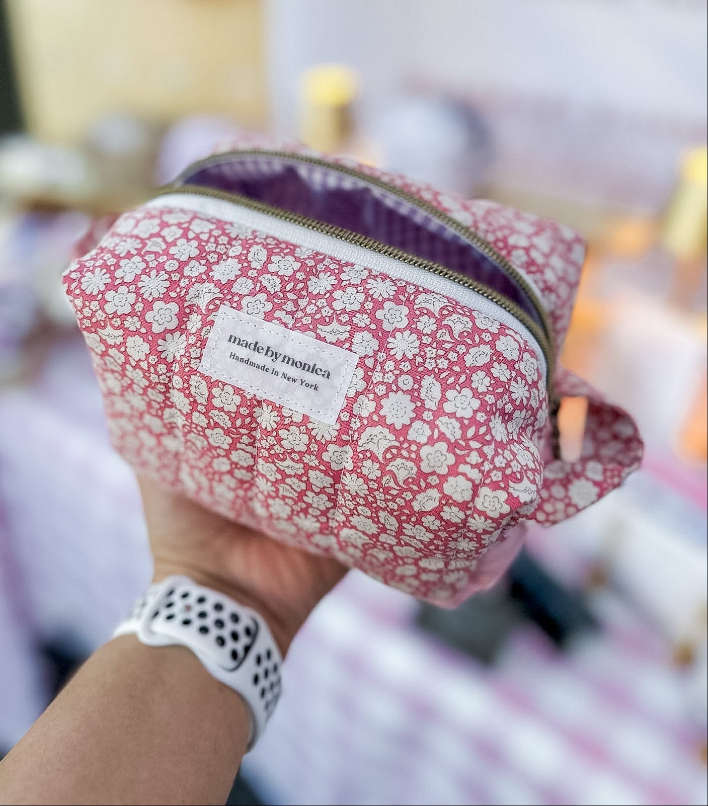 Floral-patterned pouch held by a person with a blurred background