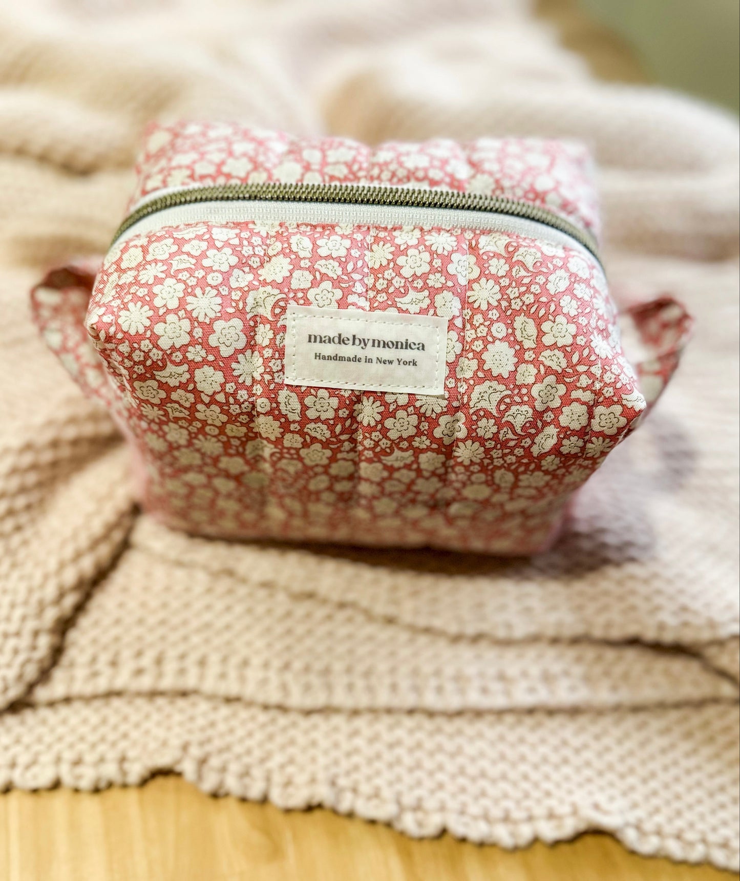 Pink floral-patterned pouch with a label on a textured surface