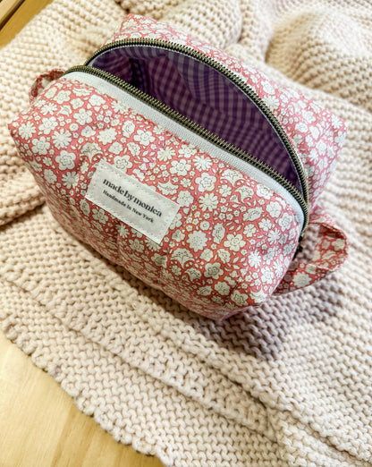 Floral-patterned pouch with a visible brand label on a textured surface