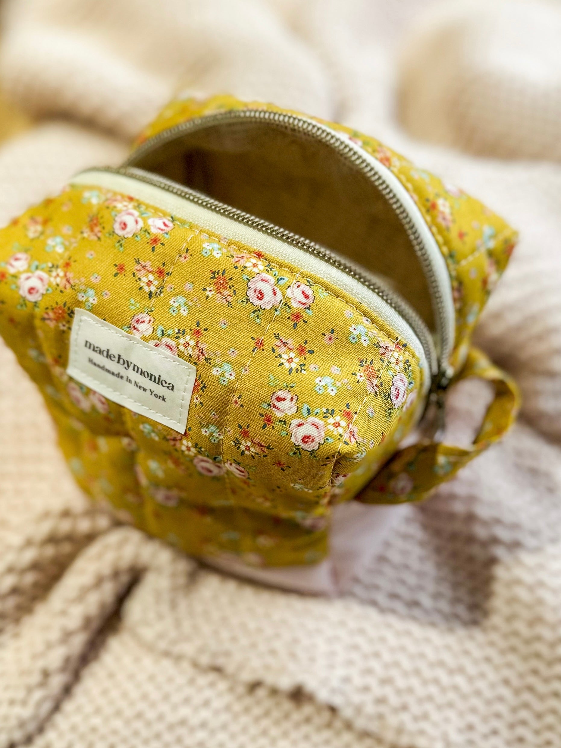 Floral-patterned bag with a visible brand label on a textured beige background