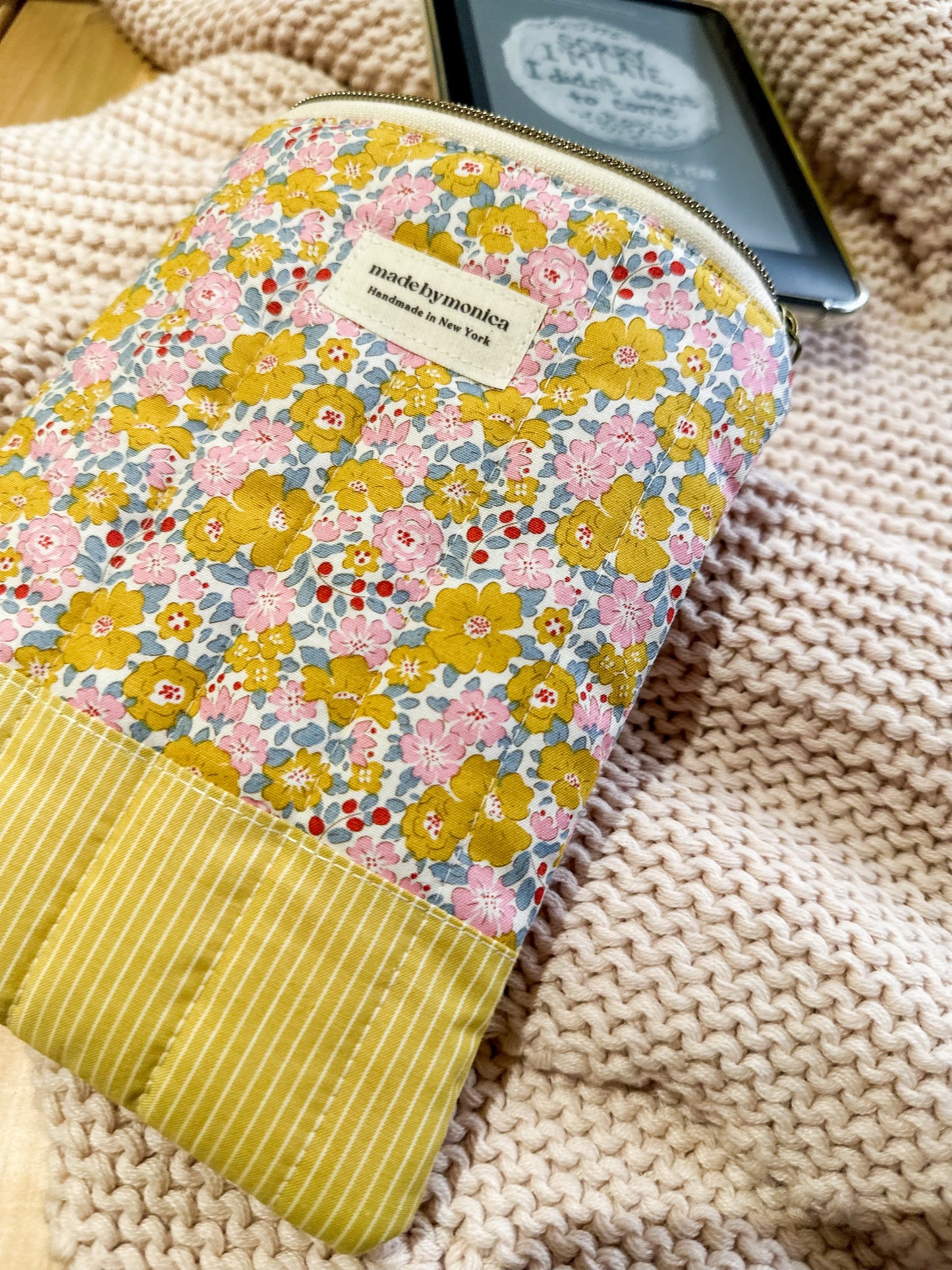 Floral-patterned pouch with a yellow stripe on a textured surface