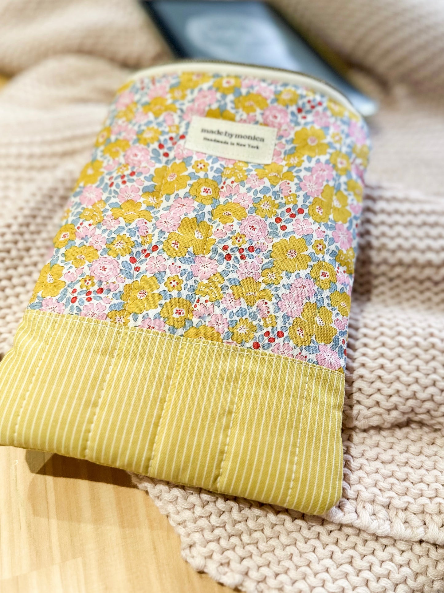 Floral-patterned pouch with a yellow base on a textured surface