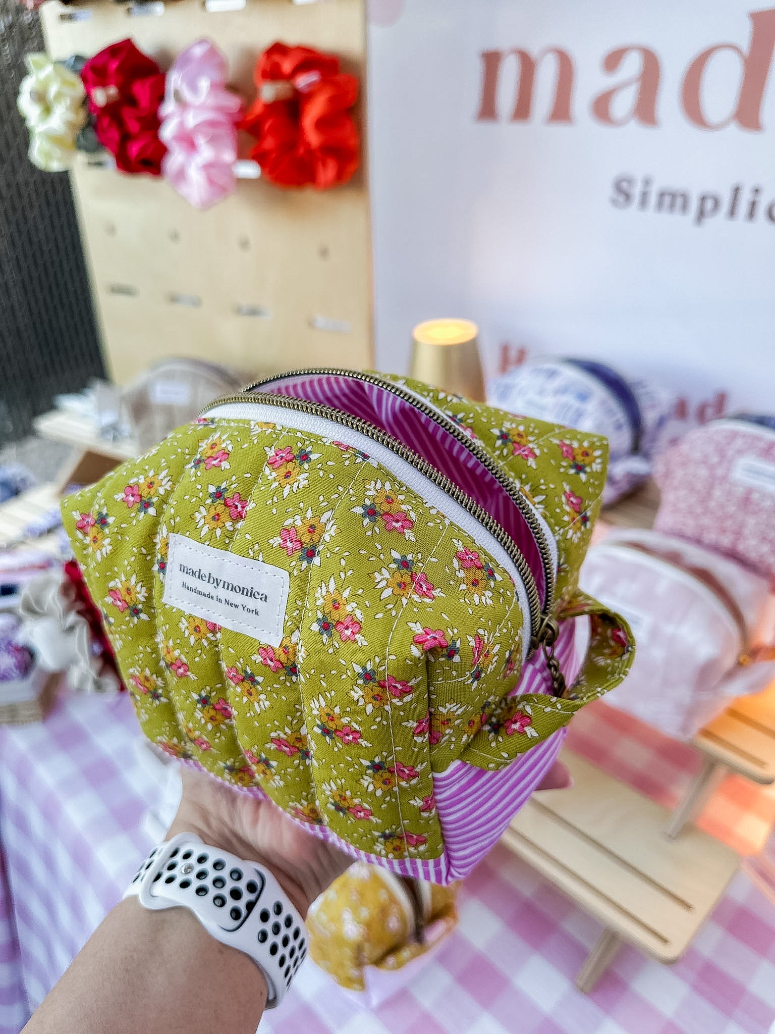 Handmade green fabric pouch with floral pattern held by a person, with a blurred background.