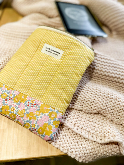 Yellow fabric pouch with floral pattern on a textured surface
