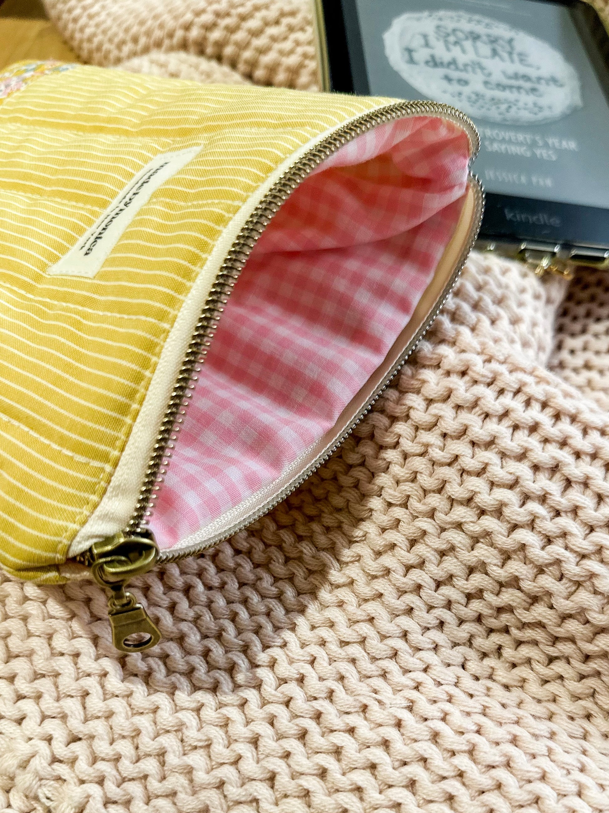 Yellow textured pouch with pink interior on a textured surface