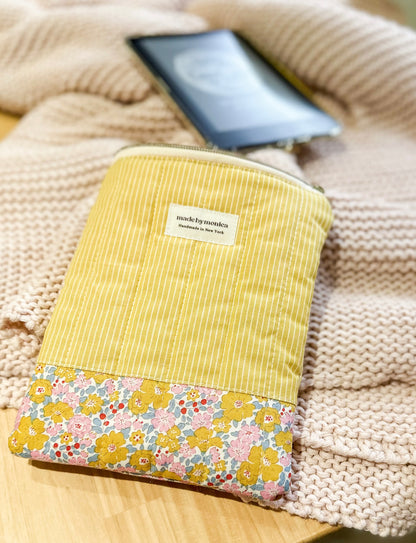 Yellow fabric pouch with floral pattern on a textured surface