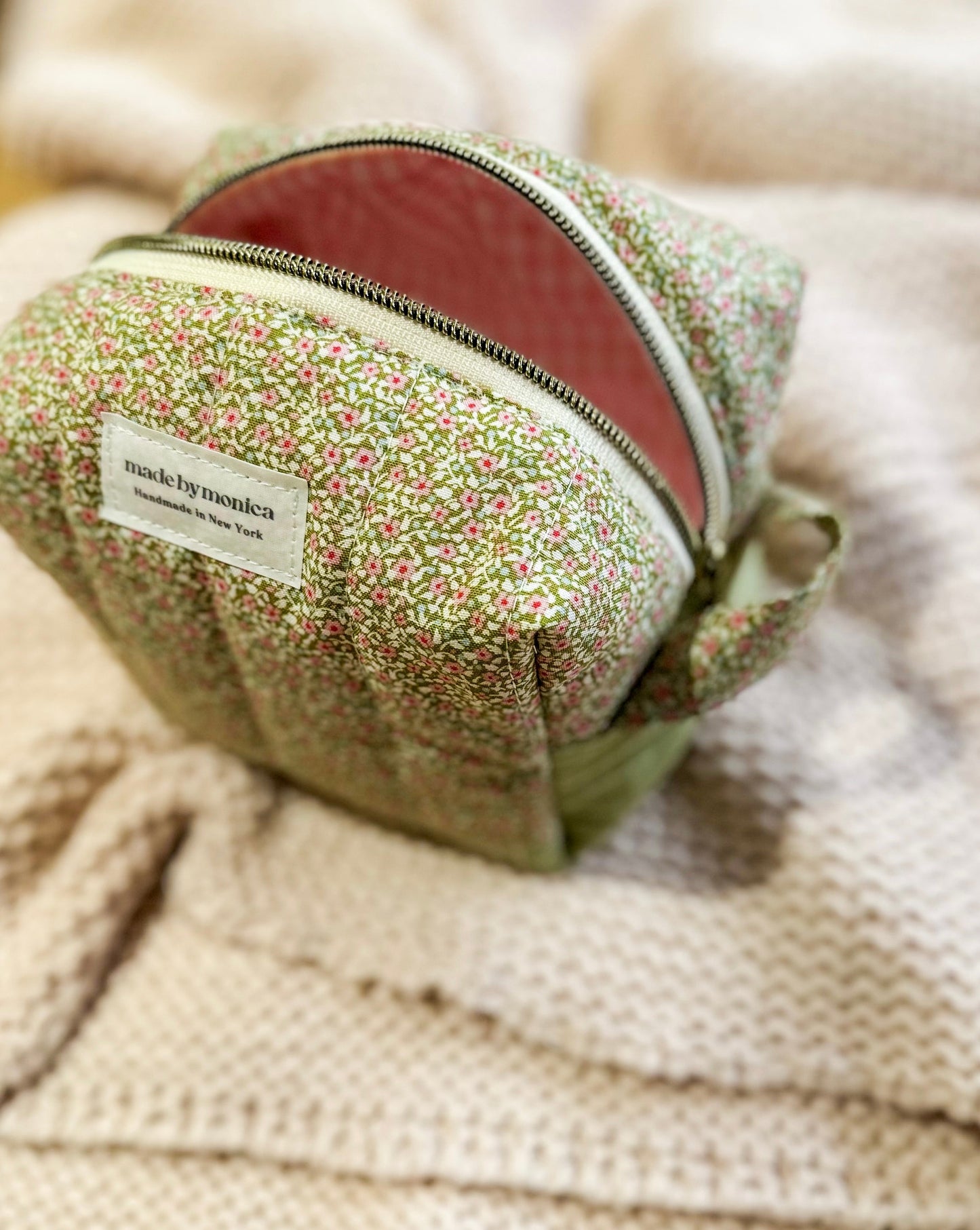 Small green fabric pouch with floral pattern on a textured beige surface