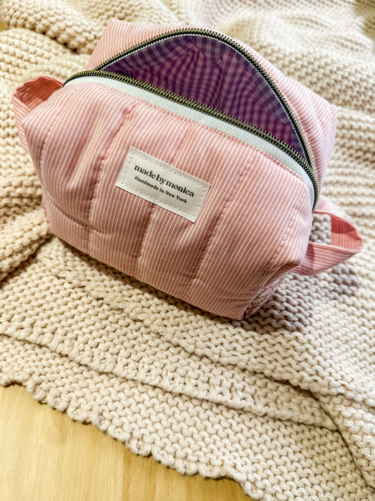 Pink pouch with a purple interior on a textured surface