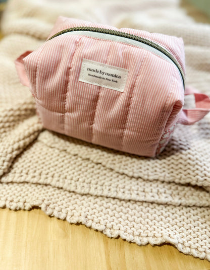 Pink pouch with a label on a textured surface